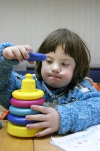 A child with Down syndrome is playing with toys